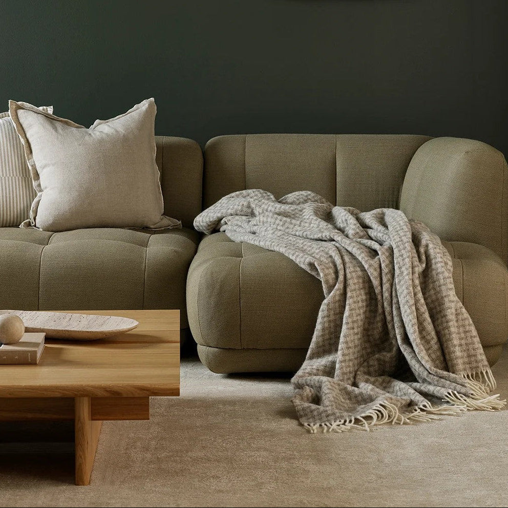 Cozy living room with a beige sofa, a wool throw, and decorative wall art.