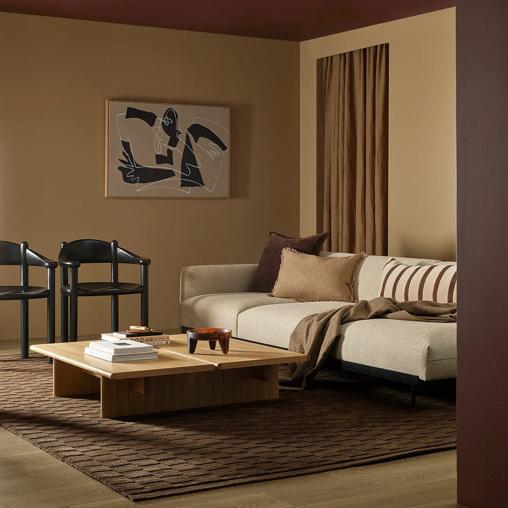 Modern living room with a beige sofa, wooden coffee table, espresso coloured floor rug and abstract art on the wall.