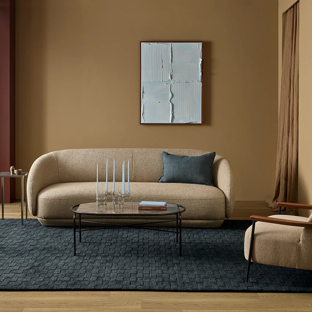 Modern living room with beige sofa, charcoal floor rug, coffee table, and abstract wall art.