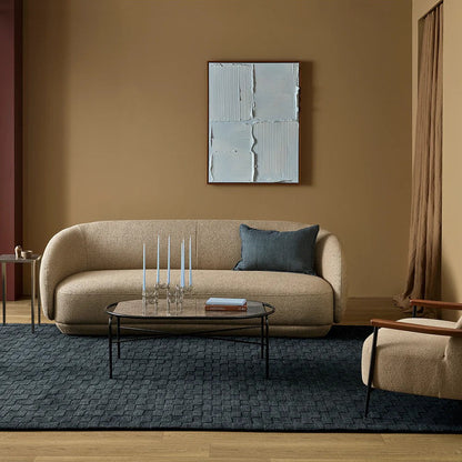 Modern living room with beige sofa, charcoal floor rug, coffee table, and abstract wall art.