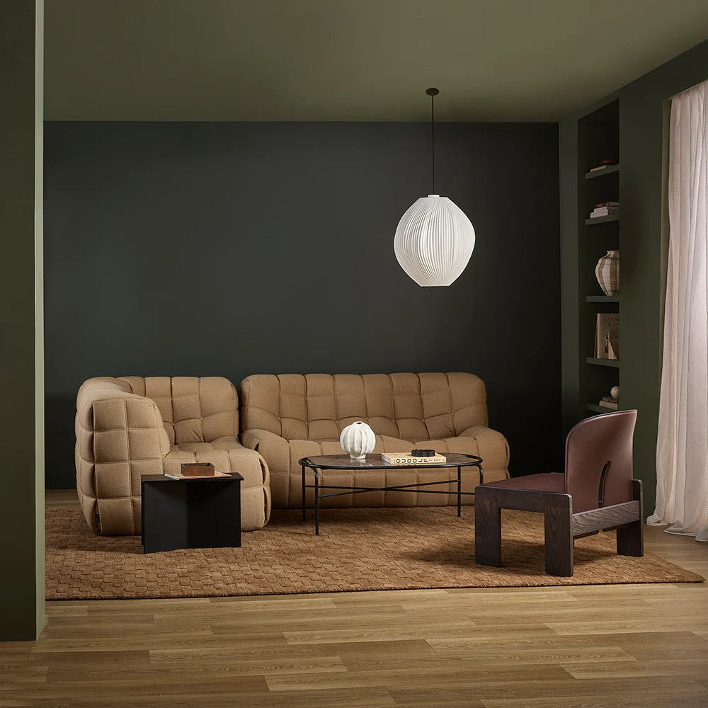 Modern living room with a beige sofa, armchair, toffee coloured floor rug and coffee table under a white pendant light.