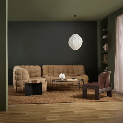 Modern living room with a beige sofa, armchair, toffee coloured floor rug and coffee table under a white pendant light.