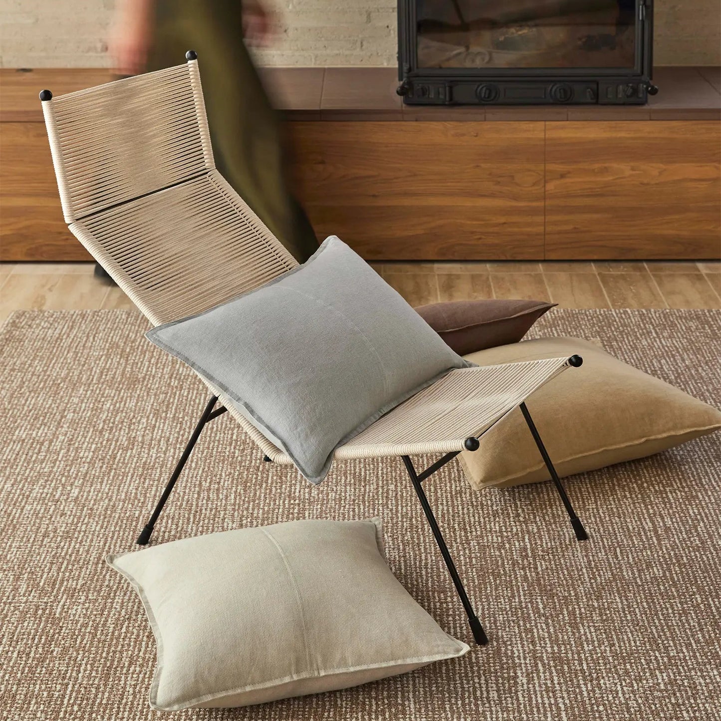 Foldable chair with cushions on a rug in a room with wooden furniture.