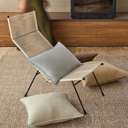 Foldable chair with cushions on a rug in a room with wooden furniture.