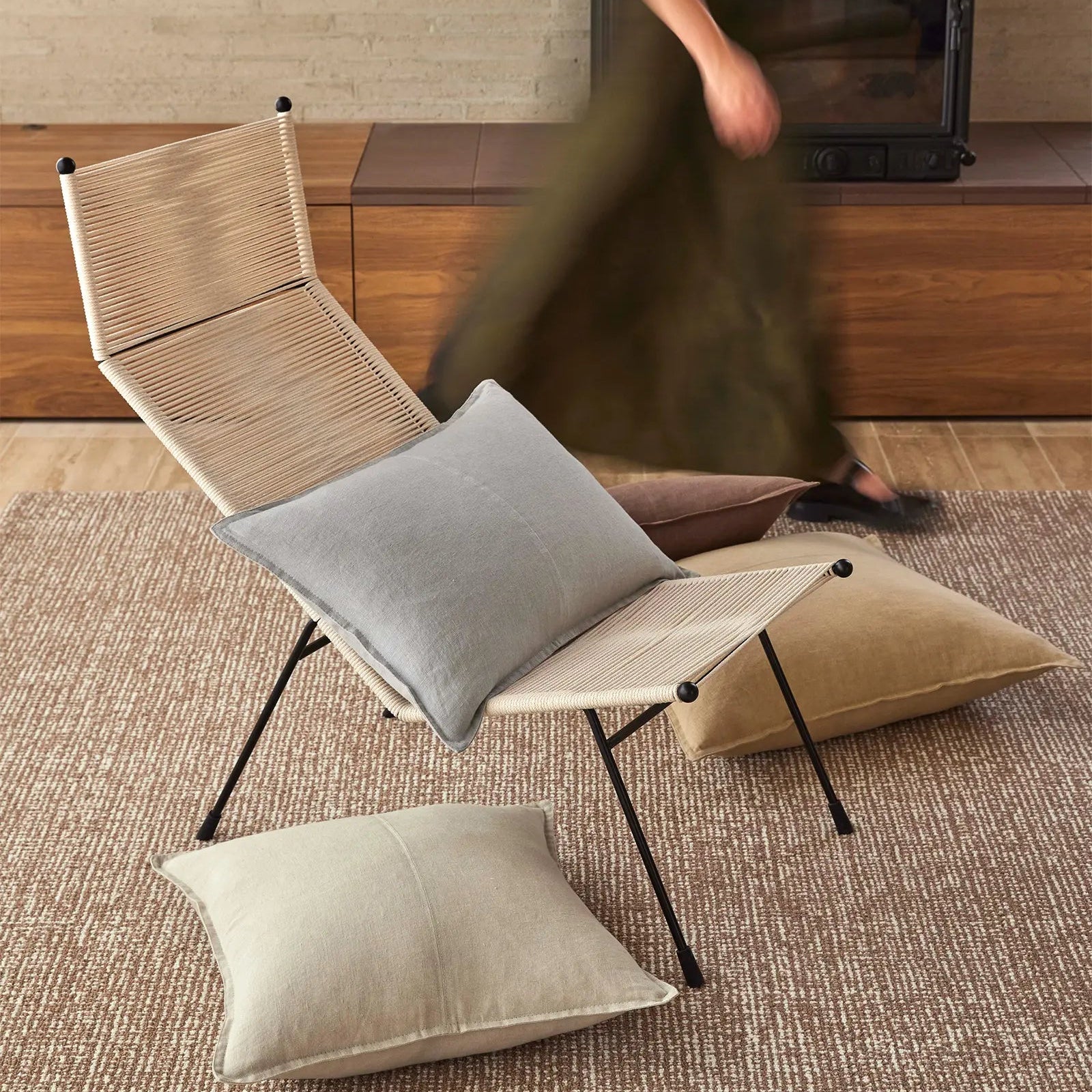 Modern chair with cushions on a textured rug in a room with wooden flooring.