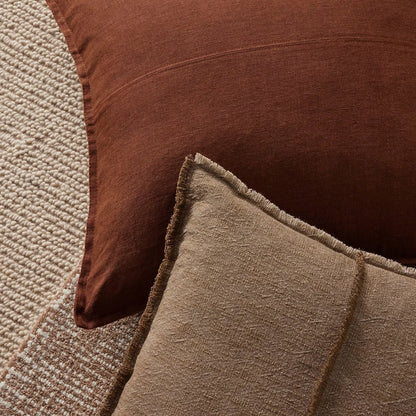 Close-up of two textured cushions, one brown and one beige, on a textured surface.