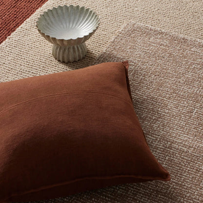 Brown cushion and decorative bowl on textured rugs