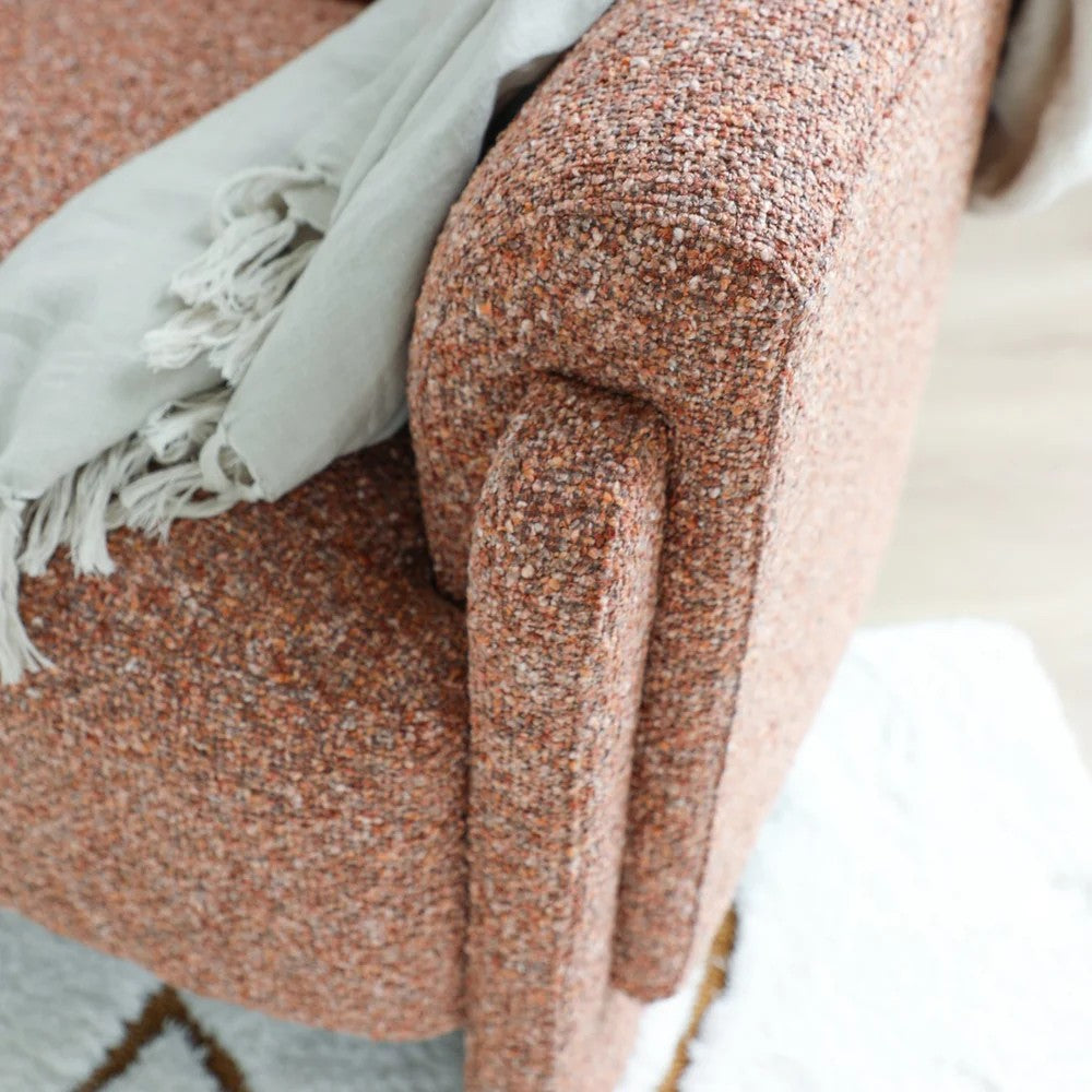Close-up of a textured armchair with a light gray blanket draped over it.