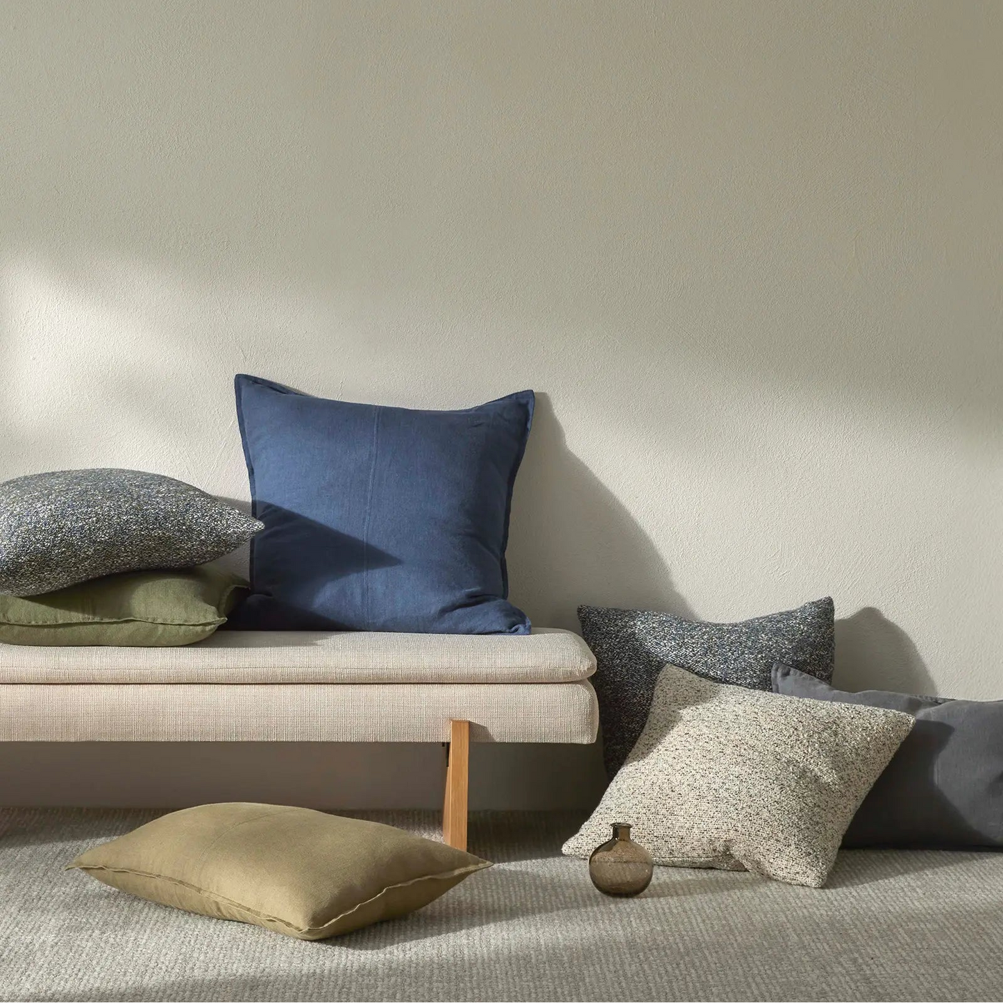 Set of cushions on a sofa against a plain wall