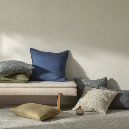 Set of cushions on a sofa against a plain wall