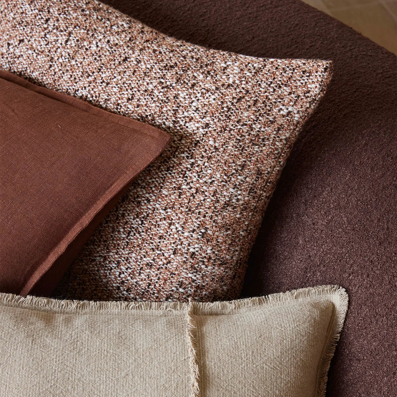 Close-up of textured cushions in brown and beige on a sofa.