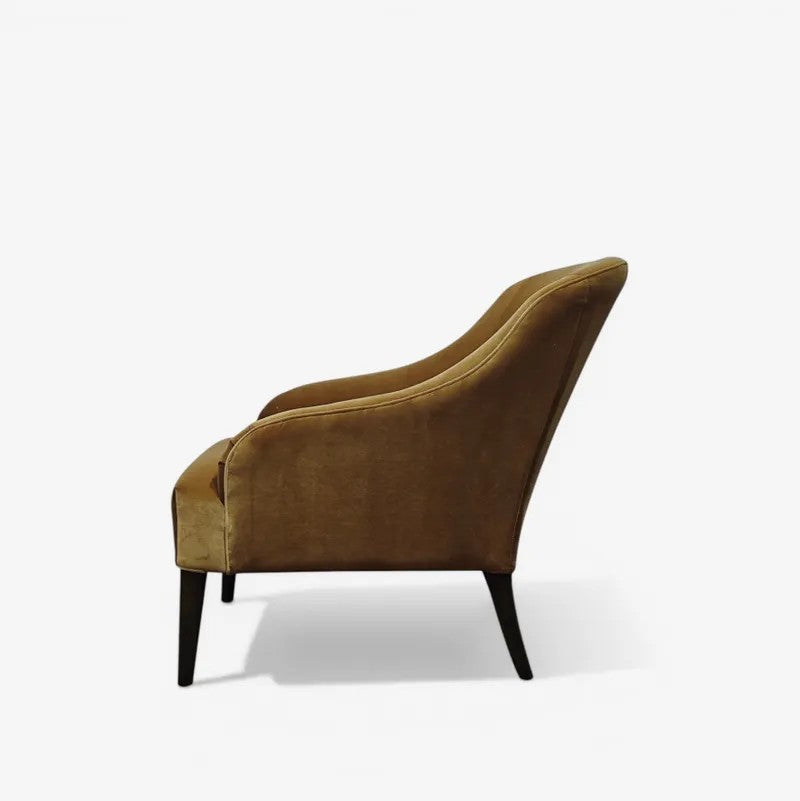 A single upholstered accent chair in a warm gold/tan velvet fabric, shown from a side profile view on a clean white background.