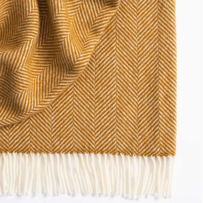 Amber herringbone patterned blanket with fringed edge on a white background