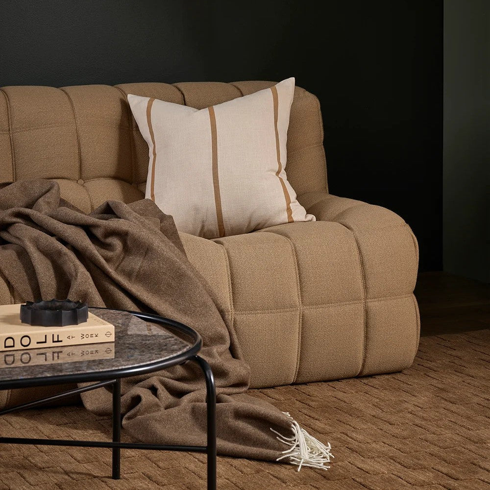 Beige sofa with a cushion and a wool blanket in a dark room