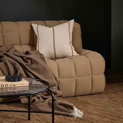 Beige sofa with a cushion and a wool blanket in a dark room