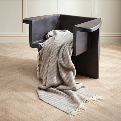 Modern chair with a oatmeal blanket on a wooden floor and panelled wall background