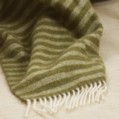Olive Green striped throw blanket with cream fringe on a beige surface