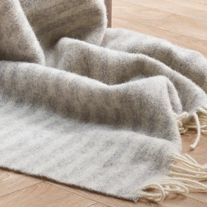 Silver Grey throw blanket with cream fringe on a wooden floor