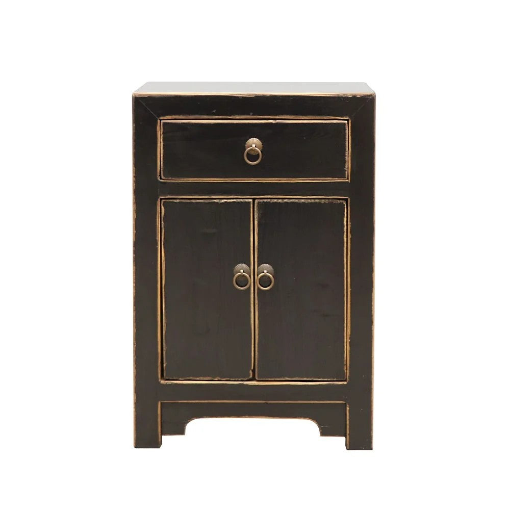 A small black bedside cabinet with two doors and a top drawer, featuring distressed natural trim and antique-style ring pulls, shown against a plain white background.