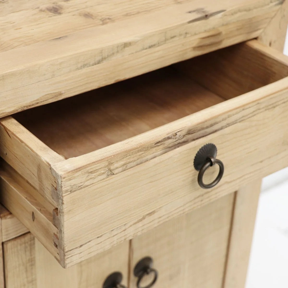 Close-up of a wooden bedside cabinet with an open drawer and metal handles.