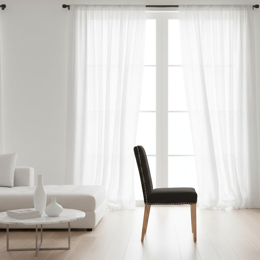 Black upholstered chair with nailhead trim on a white background