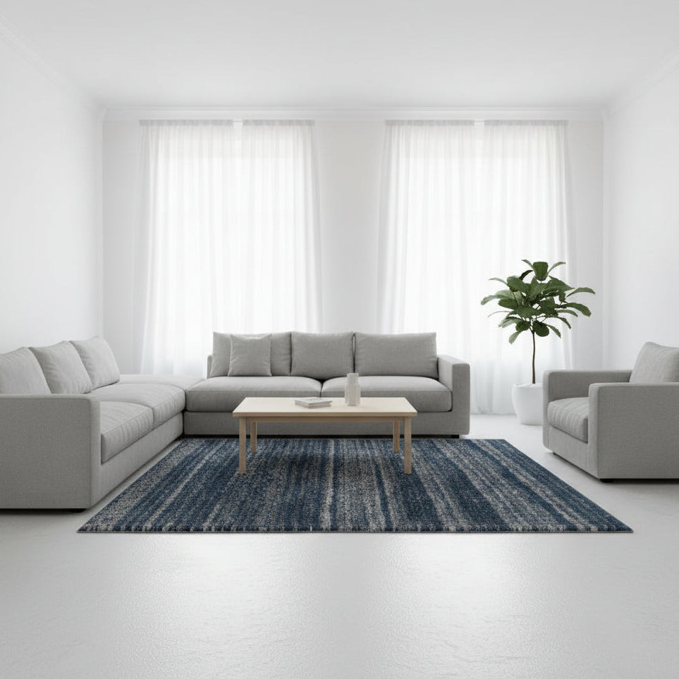 Modern living room with a gray sectional sofa, coffee table, and blue patterned rug.