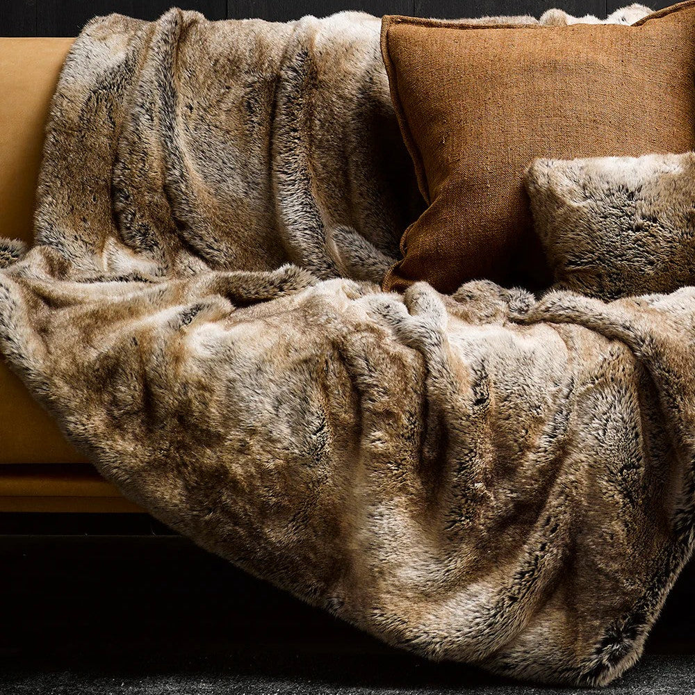 Sable fur throw draped over a sofa with matching cushions against a dark background