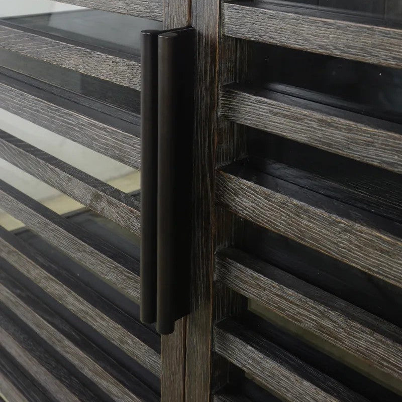 A close-up of a modern black double-pull bar handle mounted on a weathered grey wood slatted cabinet.