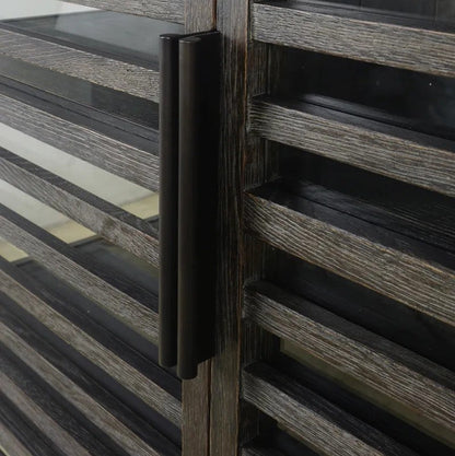 A close-up of a modern black double-pull bar handle mounted on a weathered grey wood slatted cabinet.