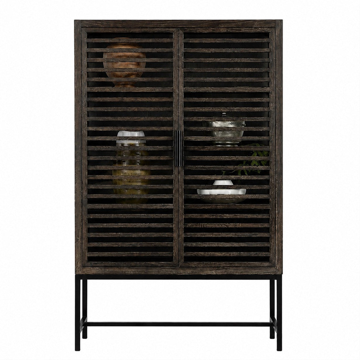 A rustic dark grey wooden cabinet with slatted doors and a black metal frame, styled with decorative glassware and ceramic vases against a plain white background.
