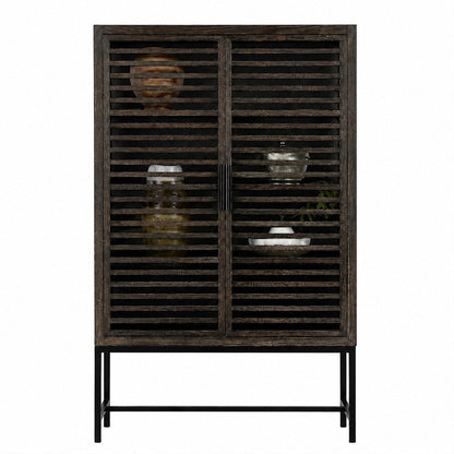 A rustic dark grey wooden cabinet with slatted doors and a black metal frame, styled with decorative glassware and ceramic vases against a plain white background.