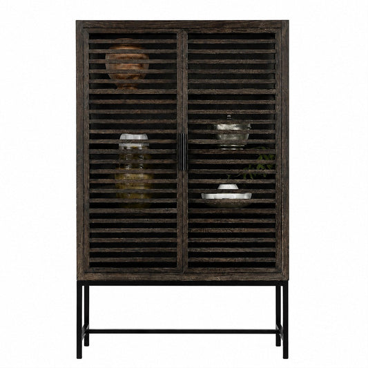 A rustic dark grey wooden cabinet with slatted doors and a black metal frame, styled with decorative glassware and ceramic vases against a plain white background.