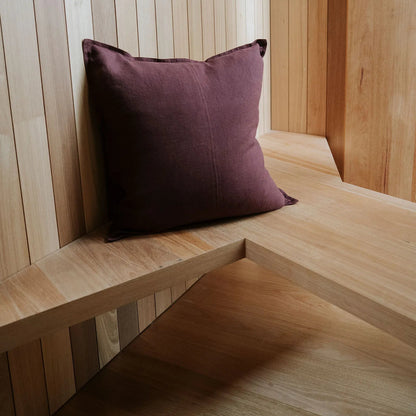 Wooden bench with a purple cushion against a wooden paneled wall.