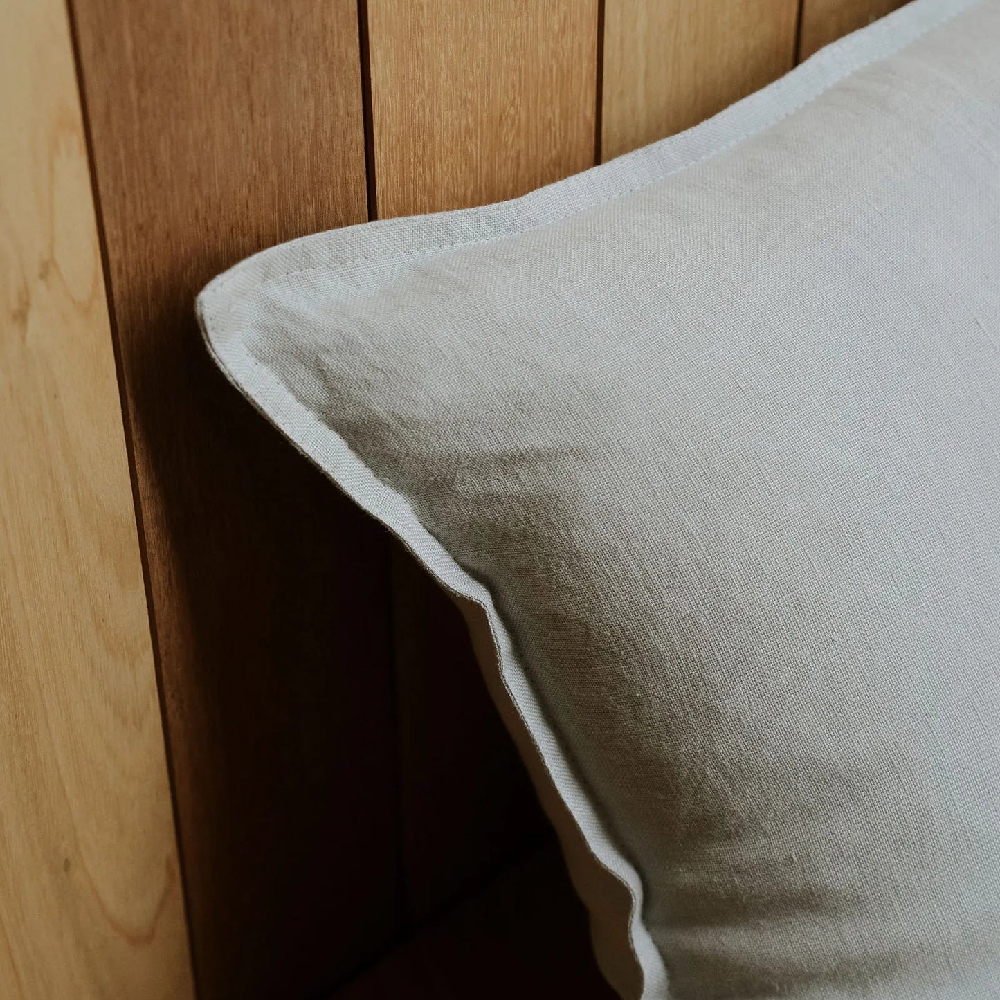 Grey pillow against a wooden headboard