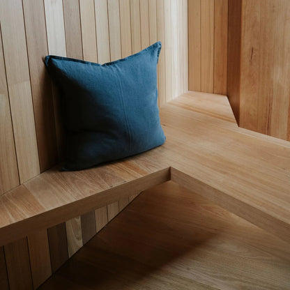 Blue pillow on a wooden bench against a wooden paneled wall