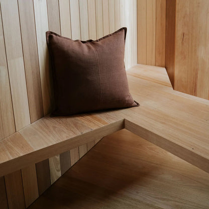 Brown cushion on a wooden bench against a wooden panelled wall