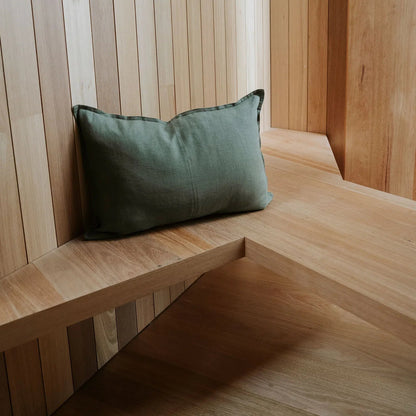 Green pillow on a wooden bench against a wooden paneled wall