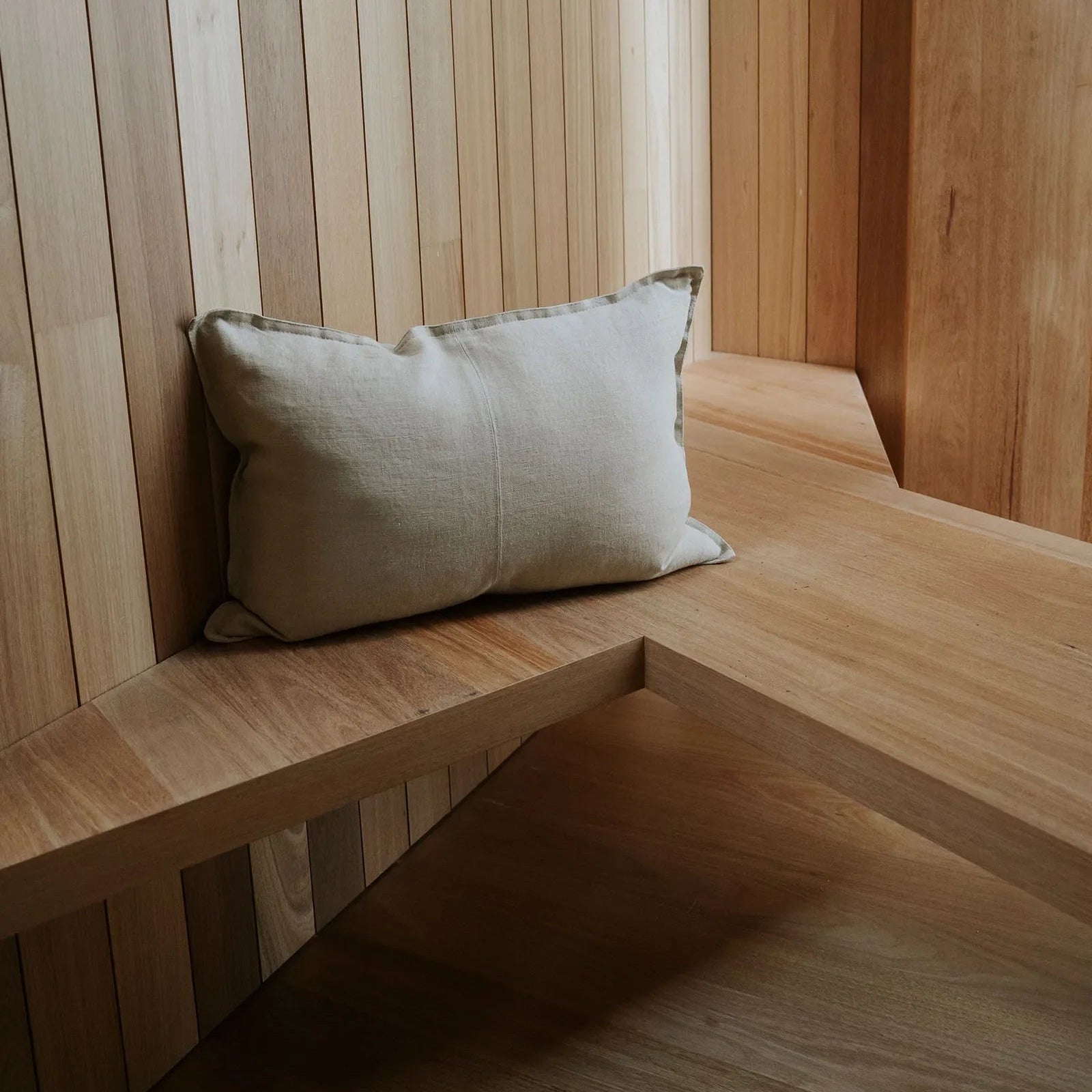 Wooden bench with a cushion against a wooden paneled wall