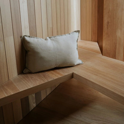 Wooden bench with a cushion against a wooden paneled wall