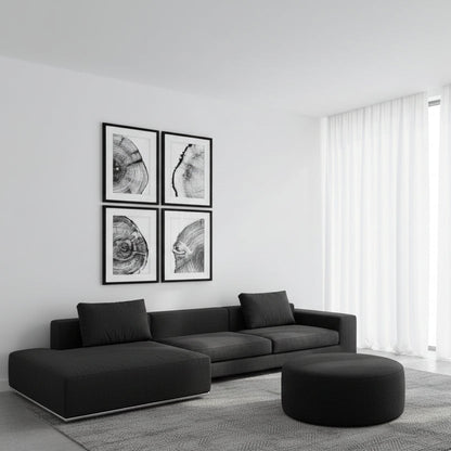 Modern living room with a black sectional sofa, ottoman, and framed art on a white wall.